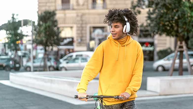 Un homme est en route avec son vélo à la main et écoute de la musique via son casque sans fil.