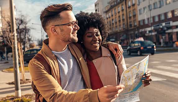 Un couple se promène dans la rue avec une carte à la main, ils sont en weekend et cherchent un endroit.