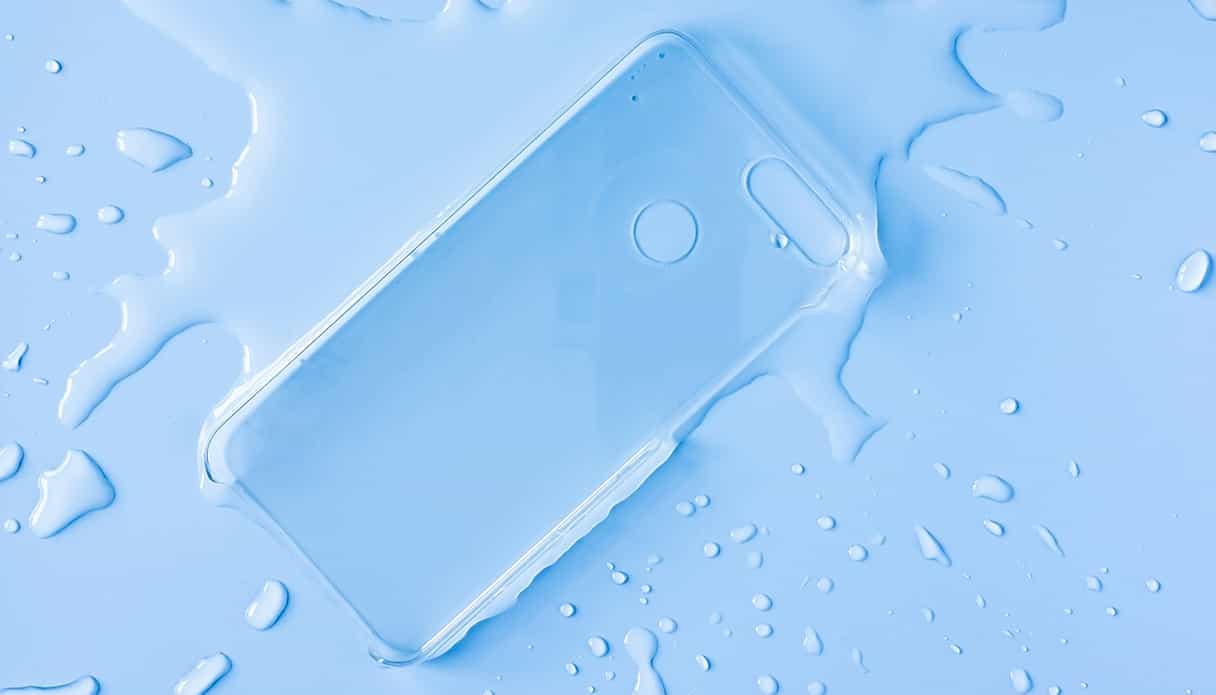 Une coque de téléphone transparente est posée dans une flaque d'eau avec des éclaboussures autour.