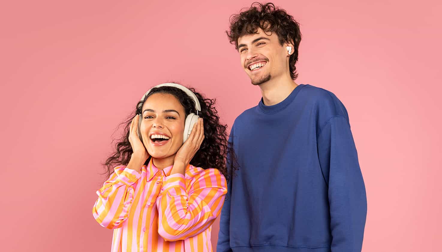 Fond rose avec deux modèles souriants, une femme avec un casque et un homme avec des écouteurs.