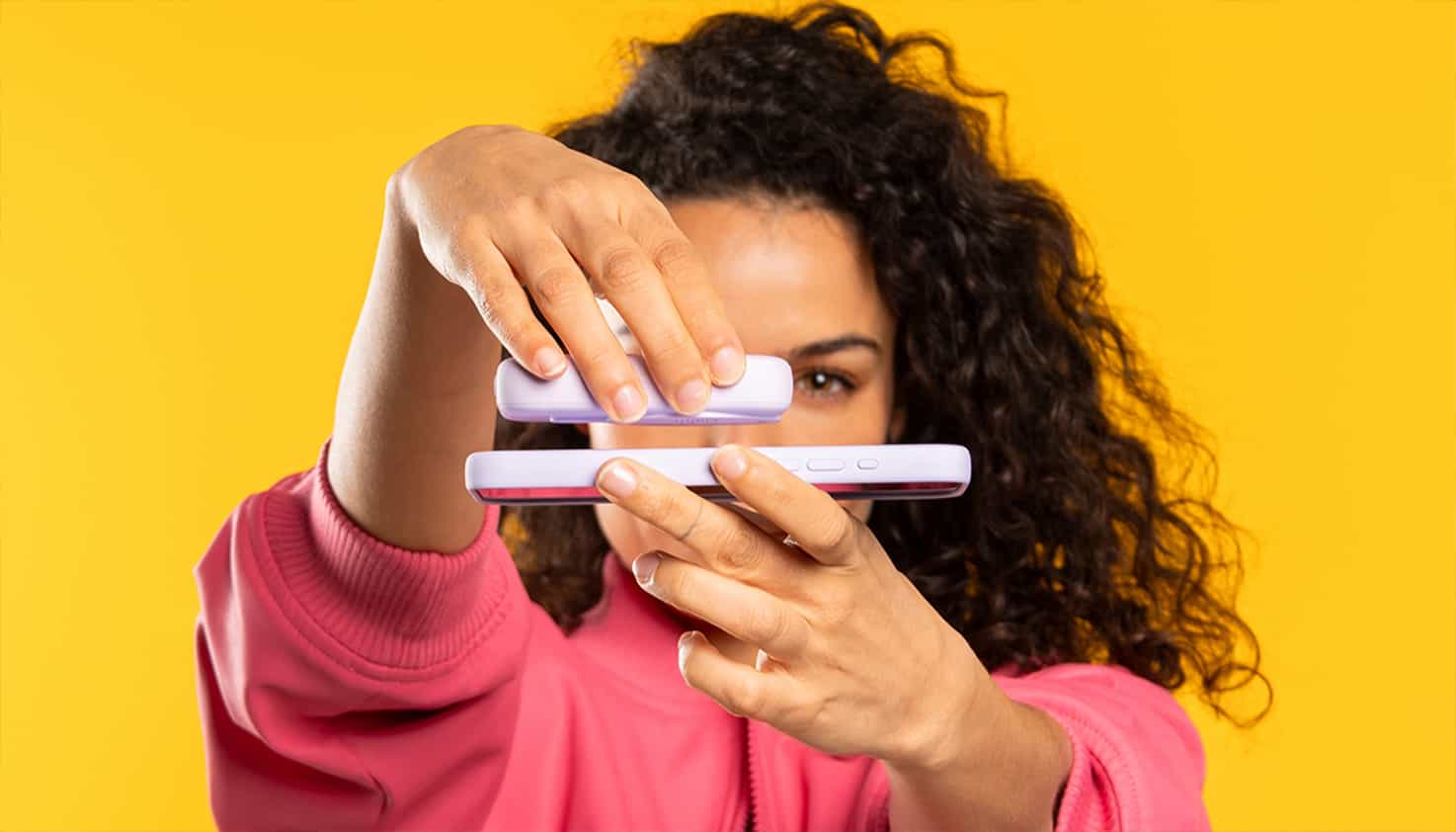 Femme au centre, accent sur la batterie MagSafe en main, tenant téléphone dans l'autre.