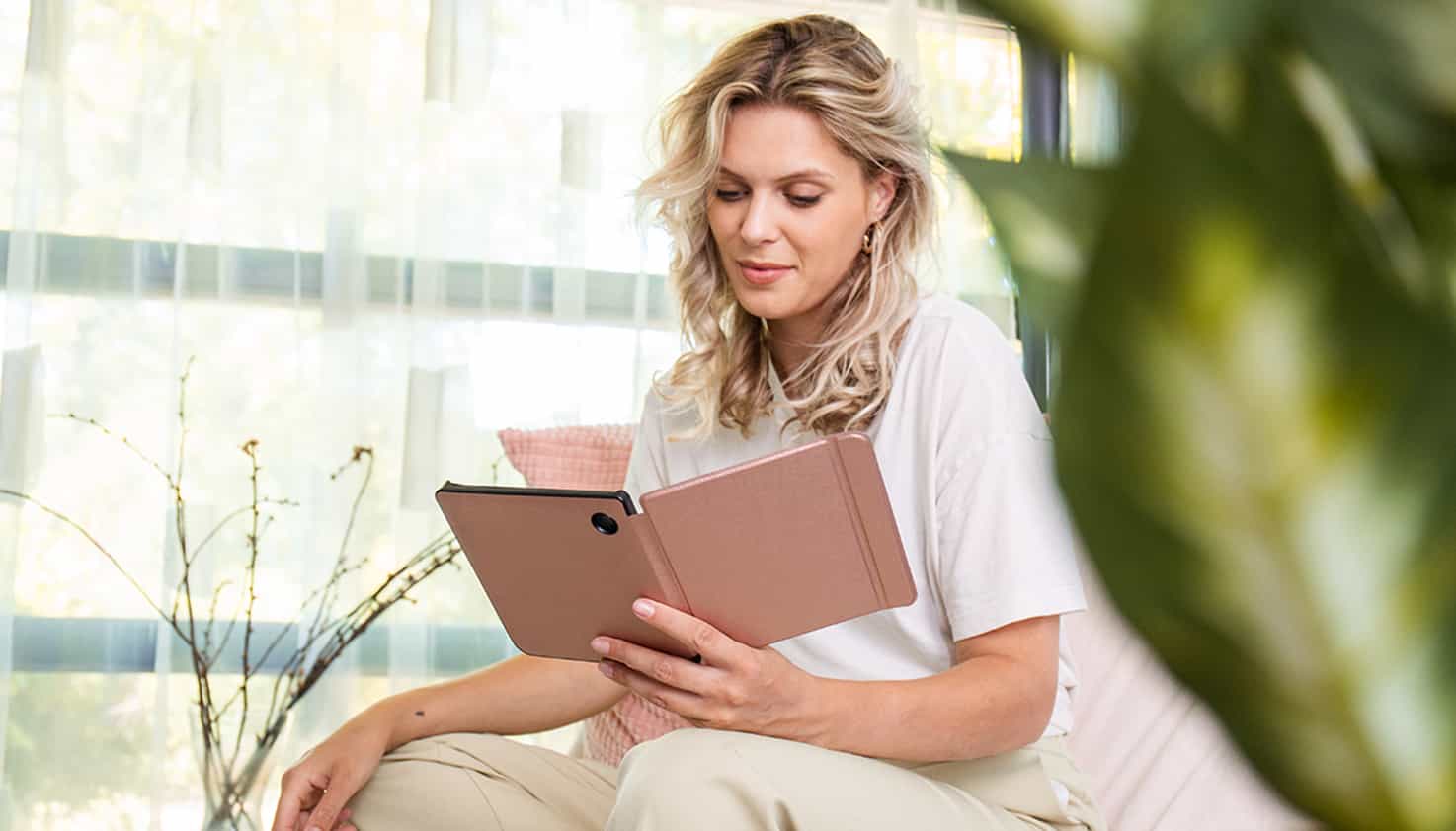 Une femme lit sur un e-reader avec une housse de Tolino.
