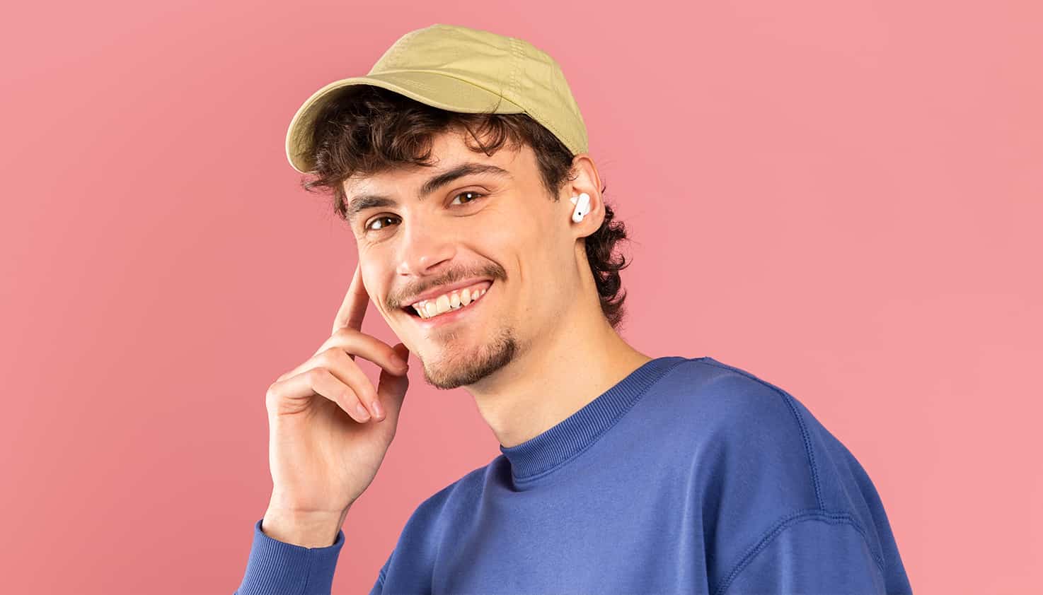 Un homme porte des Apple AirPods sans fil et sourit gentiment à la caméra.