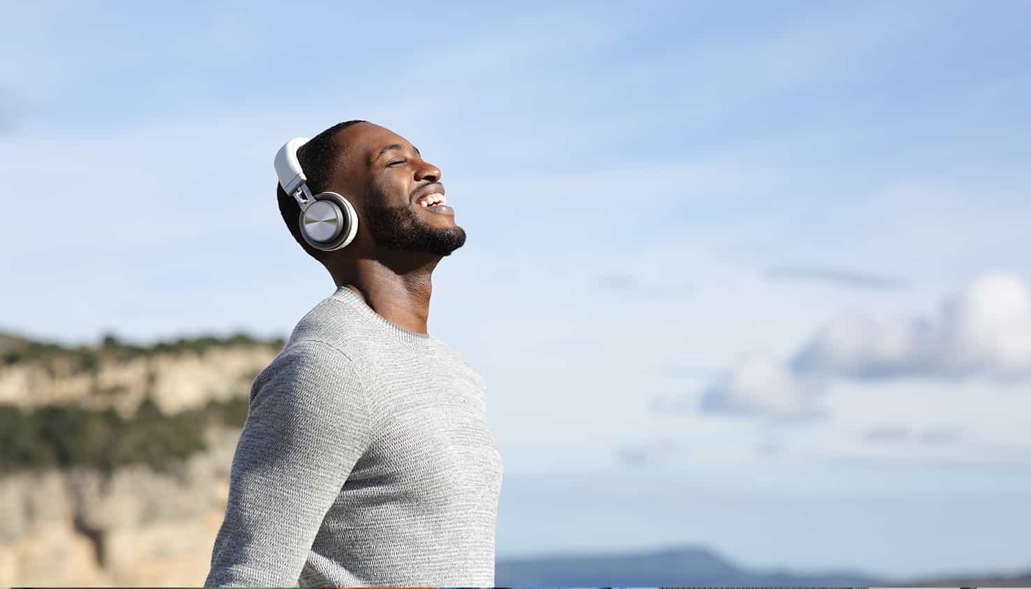 Une femme est assise sur le canapé avec un casque sans fil, en train d'écouter sa chanson préférée.