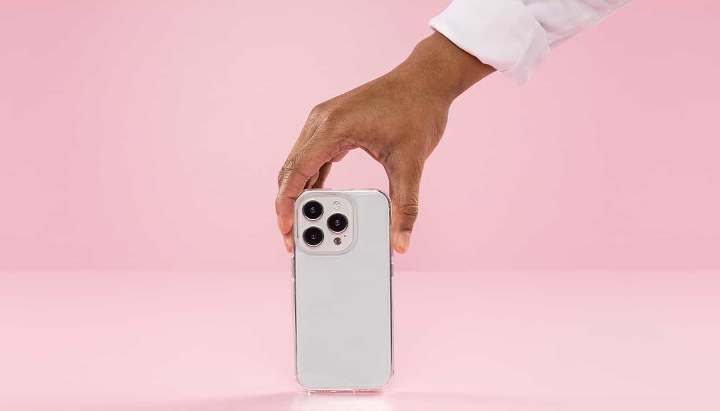 La coque de téléphone transparente est au centre et est tenue par une main venant du haut.