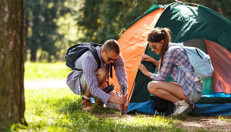 Le couple monte la tente, ils font du camping dans la forêt.